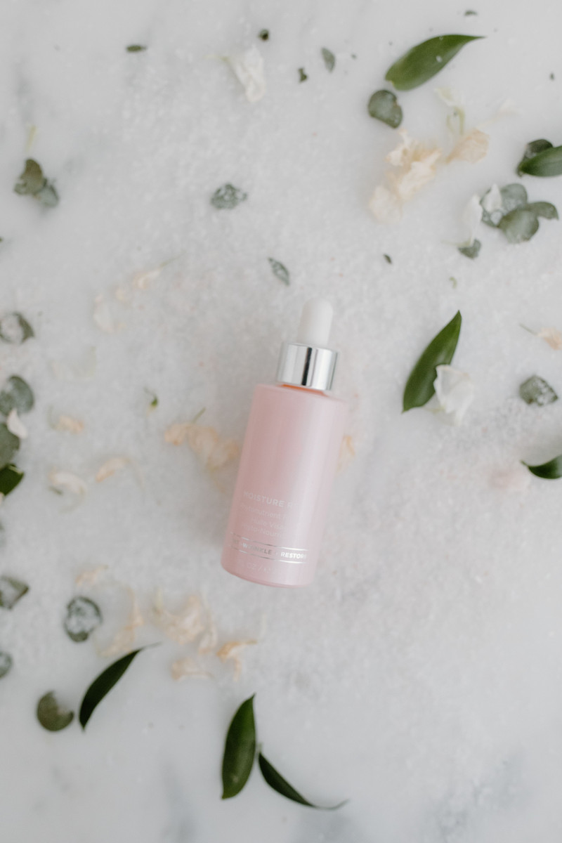 A pink dropper bottle among scattered petals.